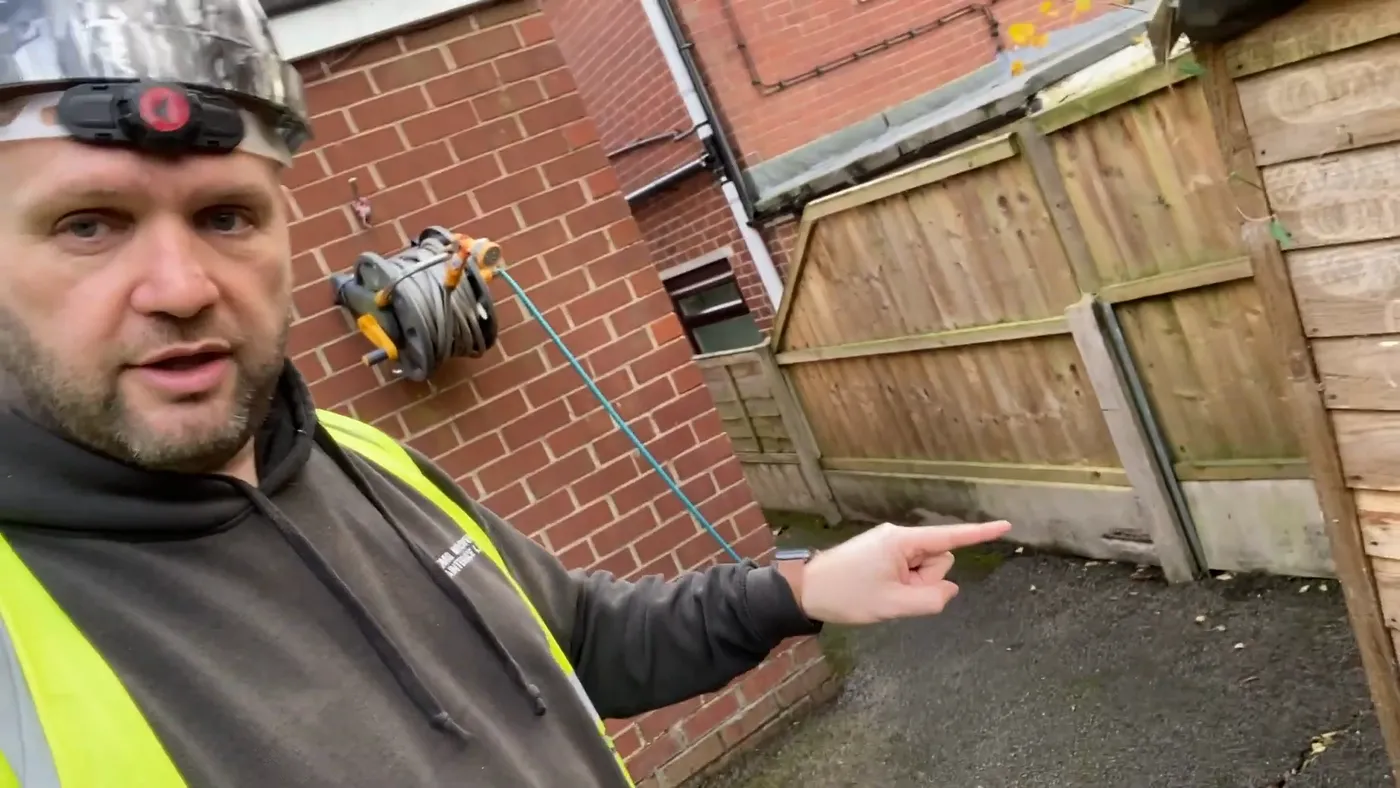 John pointing down towards the ground where the property meets the neighbouring boundary.
