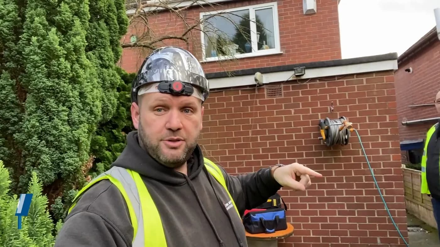 John pointing at the incoming electricity service cable running down external brickwork into the house.