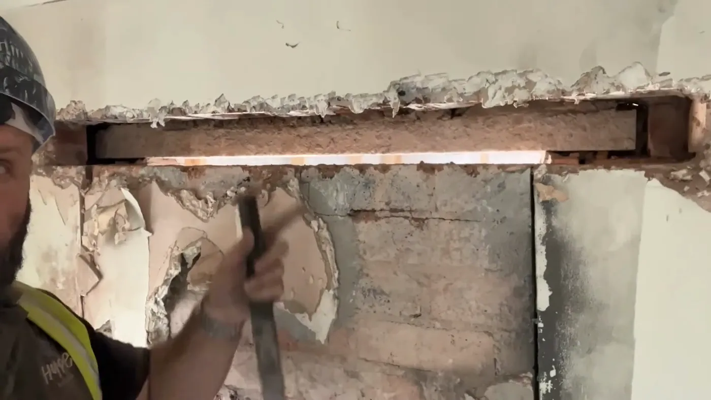 A concrete lintel bedded on sand and cement, spanning a new opening, with the brickwork below still in place.