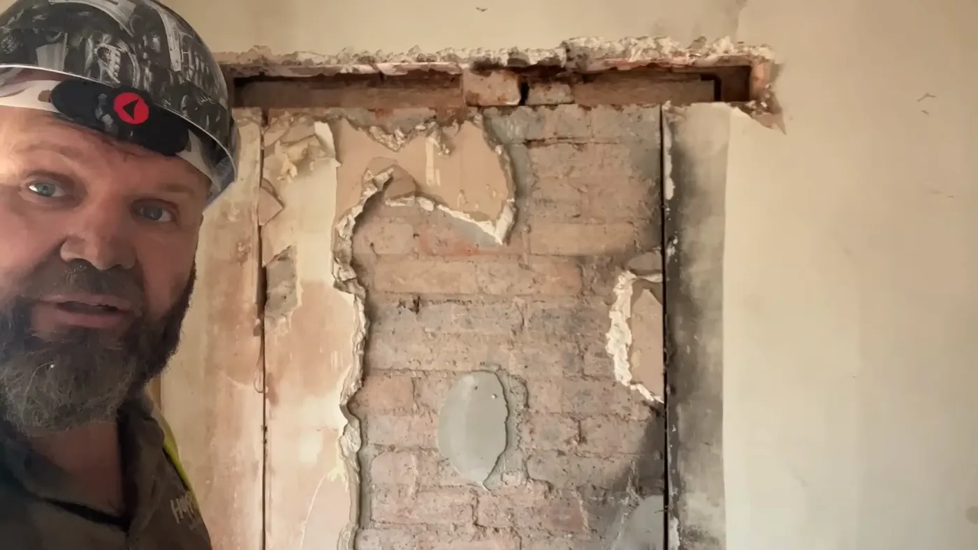 A wall with the plaster chased off to expose the masonry, with the new opening marked out.