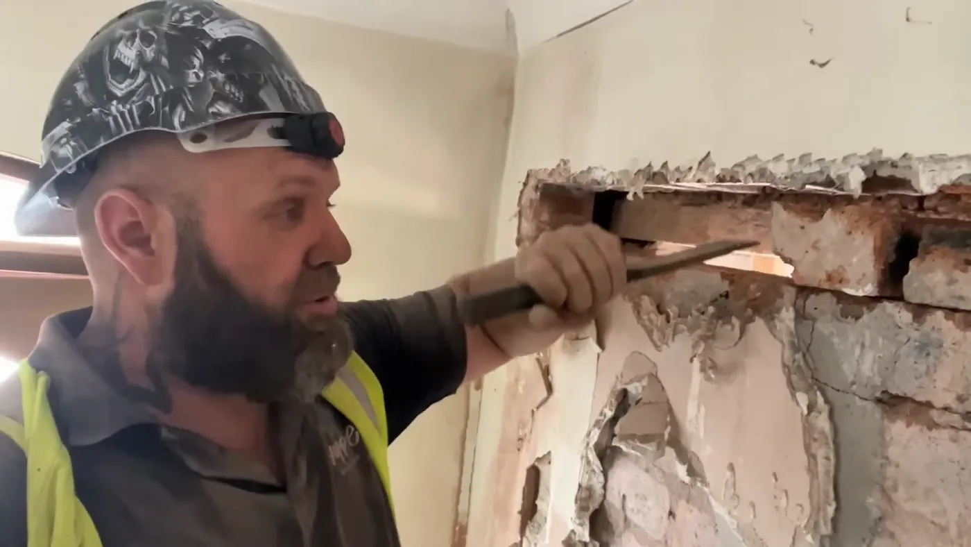 John using a bolster chisel to take out brickwork beneath an installed lintel.