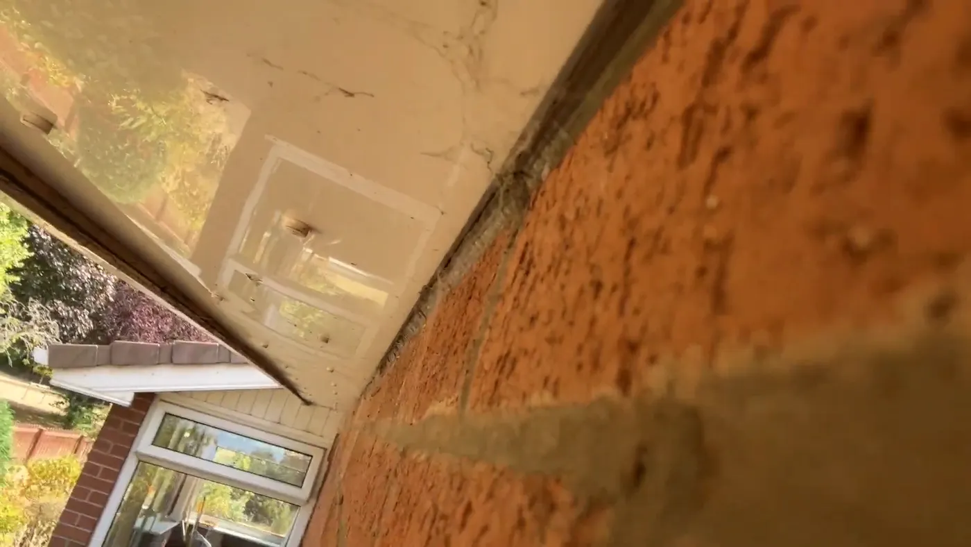 A crack running through brickwork just below the roofline of a house.