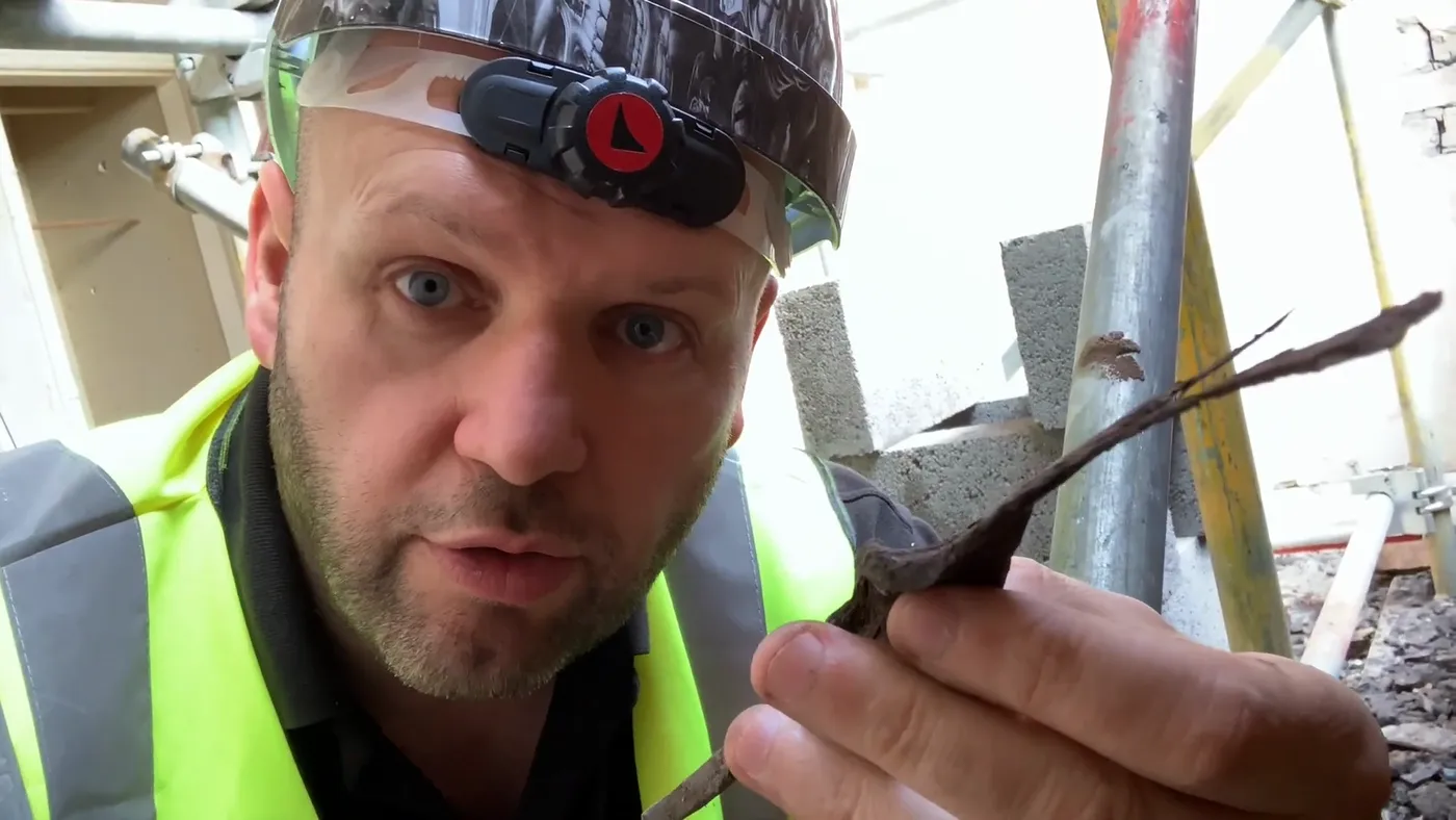 John holding up a heavily corroded steel wall tie taken out of the cavity, beside a modern replacement.