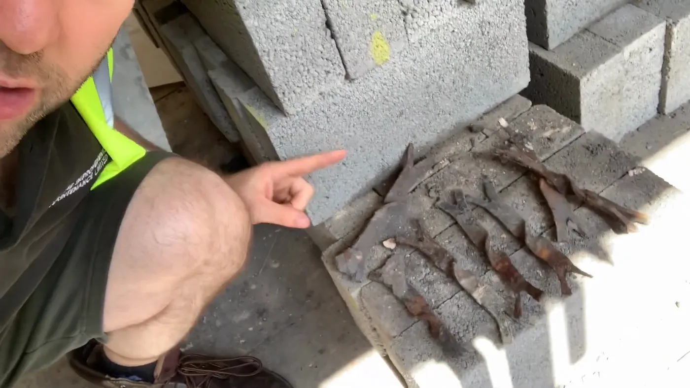 A row of old steel wall ties removed from a cavity wall, heavily rusted and flaking.
