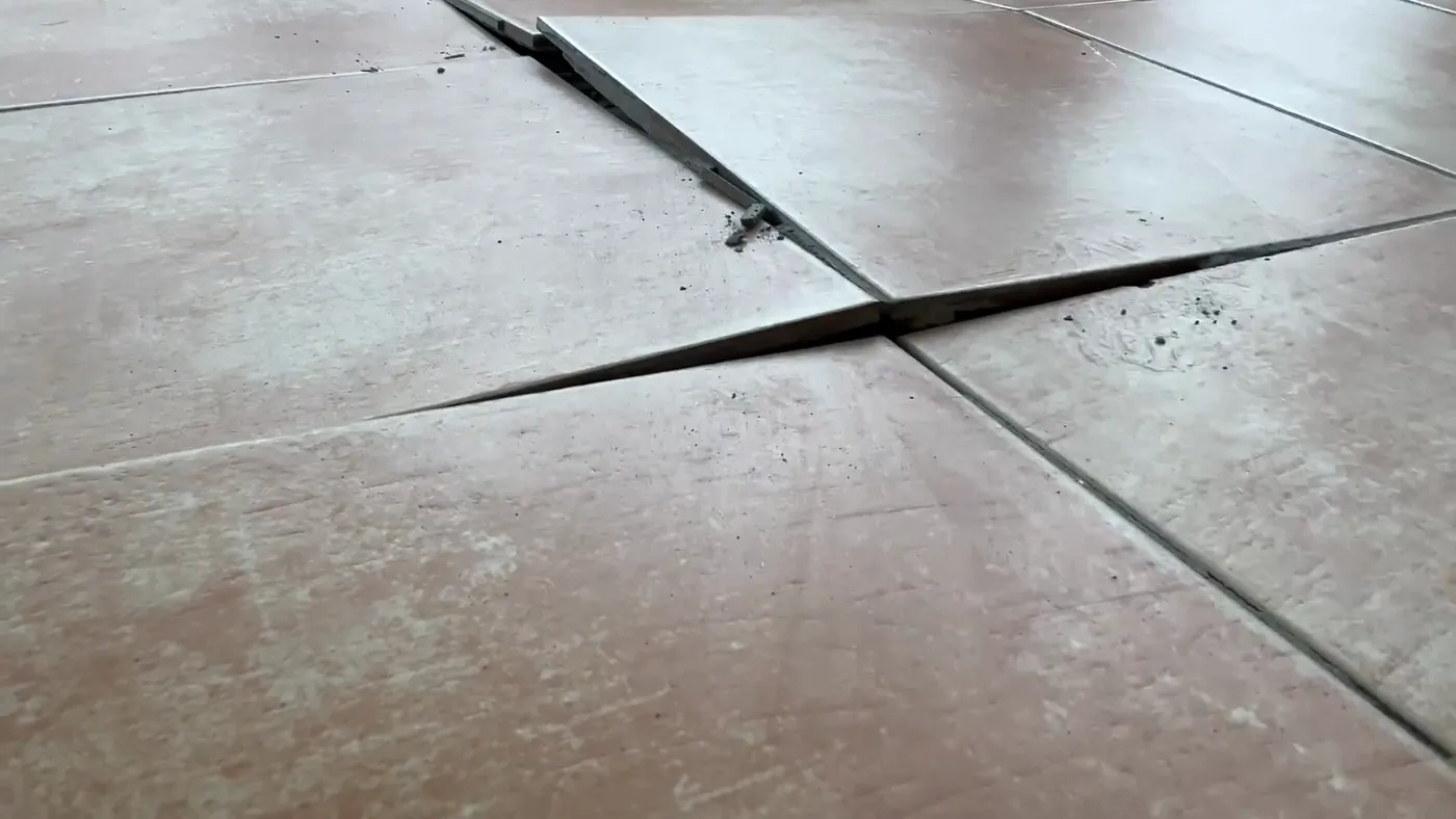Conservatory floor slabs that have lifted and separated, leaving an open gap between them.
