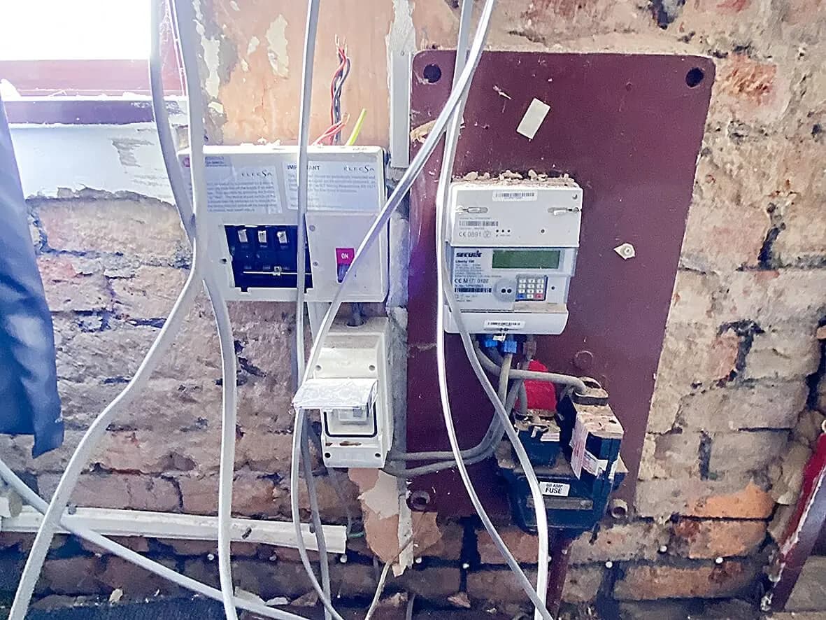 Strip-out · new consumer unit and meter board on bare brick
