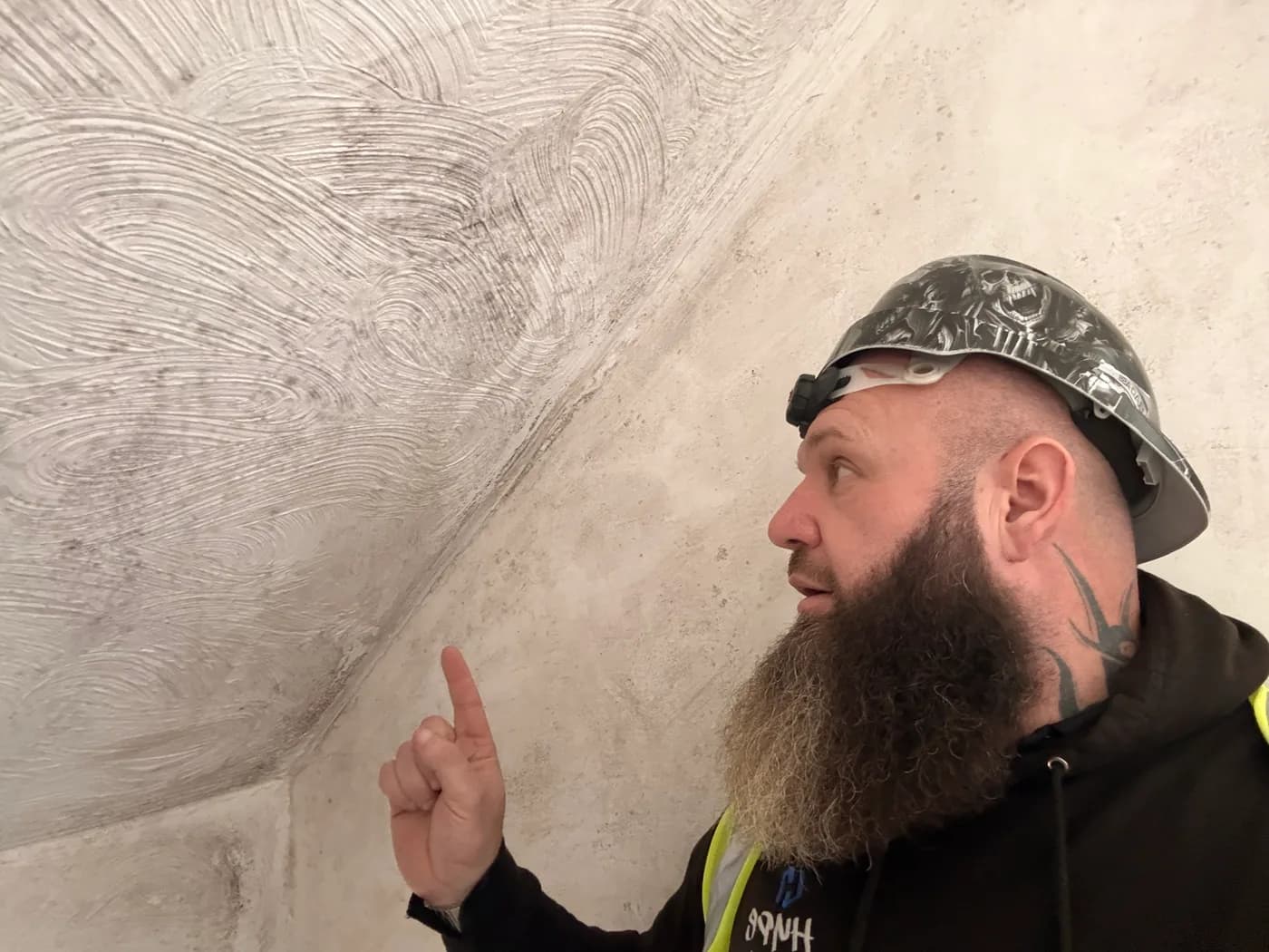 John pointing out a tide mark low down on a plastered internal wall.